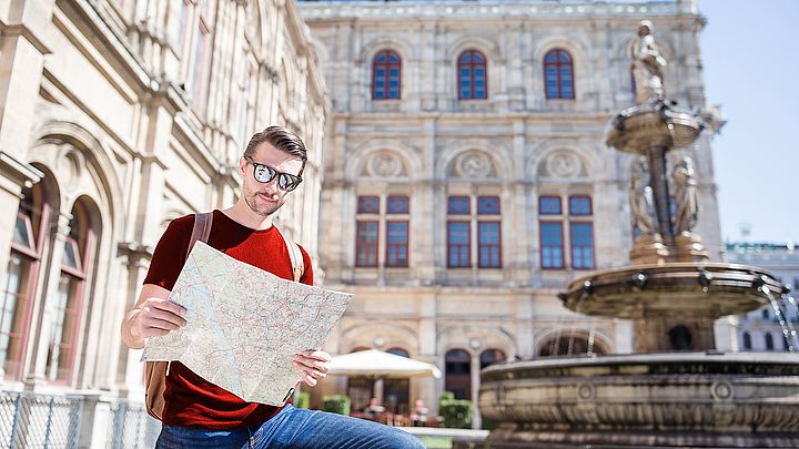 Ein Tourist steht mit dem Stadtplan vor der Wiener Staatsoper.