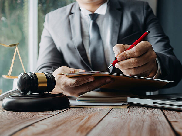 Ein Rechtsanwalt unterzeichnet einen Vertrag auf seinem Schreibtisch. 