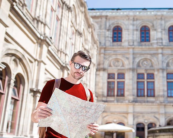 Tourist steht mit dem Stadtplan vor der Wiener Staatsoper.