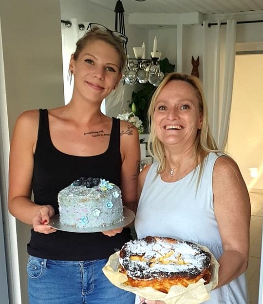 Raffaella Lang, ein Lehrling bei der Wiener Städtischen, steht neben ihrer Mutter in der Küche und hält einen Kuchen in der Hand