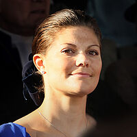 Foto von Prinzessin Victoria von Schweden mit zusammengebundenen Haaren mit blauem Oberteil.