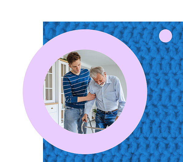 Ein junger Mann mit kurzen braunen Haaren stützt einen älteren Herrn mit weißem Haar am Rollator, beide sind in blauen Farben gekleidet. 