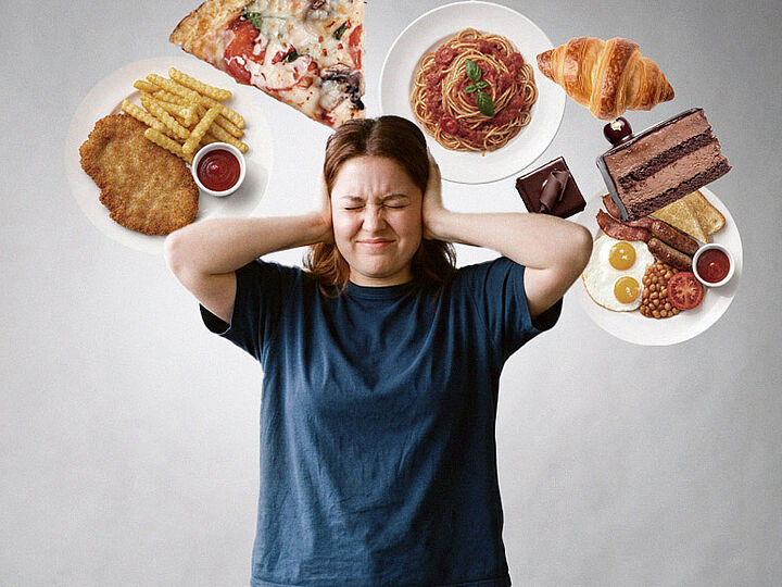 Eine Frau hält sich gestresst die Ohren zu, während um ihren Kopf verschiedene fettige und süße Speisen wie Pizza, Schnitzel, Pasta und Kuchen schweben.