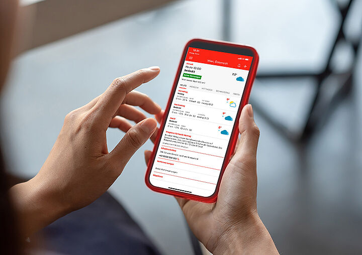 Hände mit Smartphone auf dem die Wetter App geöffnet ist.