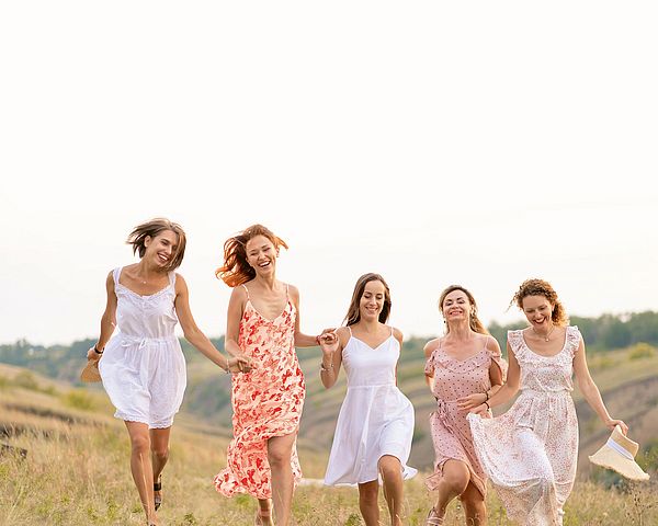 Eine Gruppe junger glücklicher Frauen läuft über ein Feld.