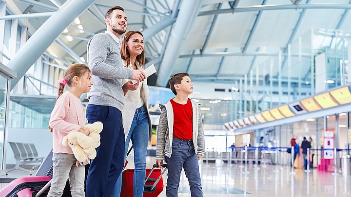 Eine junge Familie wartet voller Freude am Flughafen auf ihren Abflug in den Urlaub.