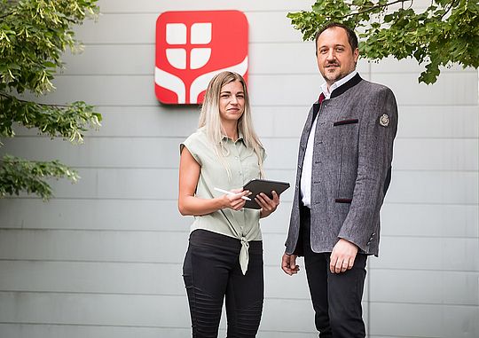 Ein Mann und eine Frau stehen vor dem Logo der Wiener Städtischen.