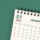 Ein weißes Kalenderblatt zeigt den Januar und liegt auf einem grünen Hintergrund.