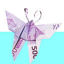 Ein aus einem 500-Euro-Geldschein gefalteter Schmetterling auf weiß-hellblauem Hintergrund