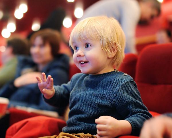 Ein Bub sitzt voller Vorfreude im Kinosaal und schaut gespannt auf die Leinwand