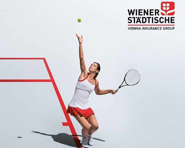Junge Frau spielt Tennis und macht gerade einen Aufschlag.