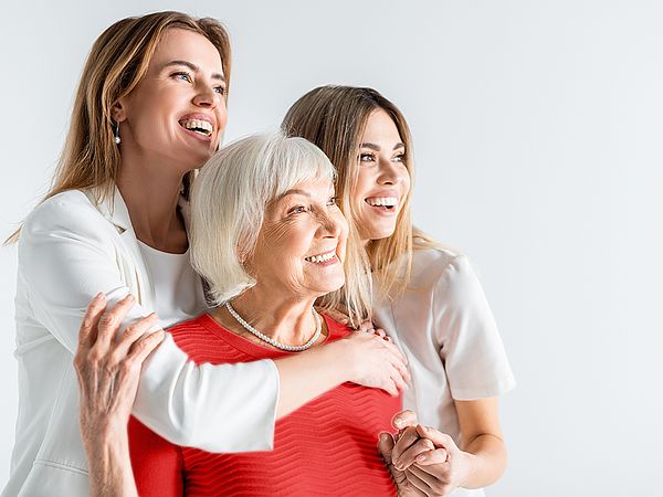 Drei glückliche Frauen verschiedener Generationen umarmen einander.