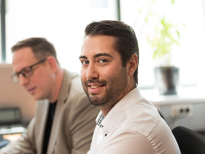 Dunkelhaariger Mann lächelt.