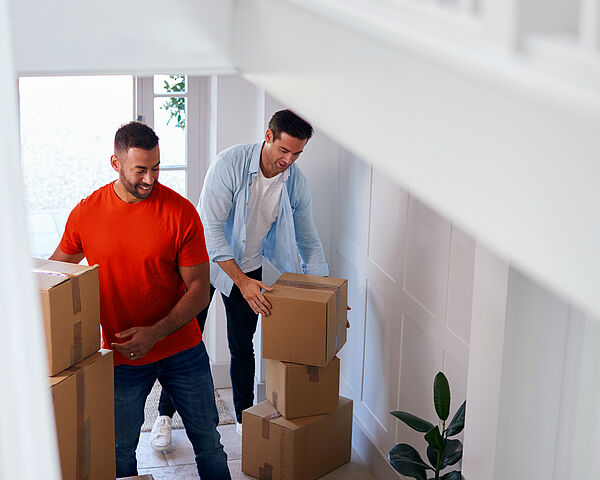 Zwei Männer tragen Umzugskartons in ihr neues Zuhause
