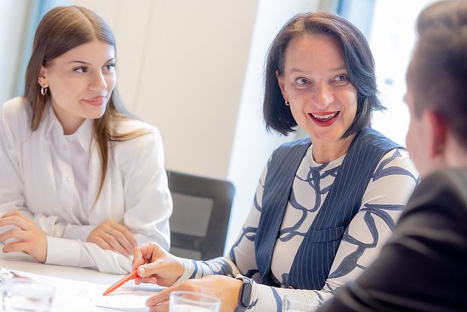 Zwei Frauen und ein Mann in einer Besprechung.