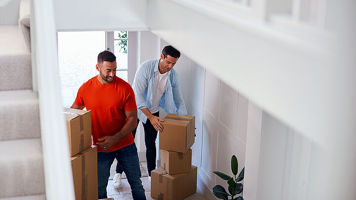 Zwei Männer tragen Umzugskartons in ihr neues Zuhause