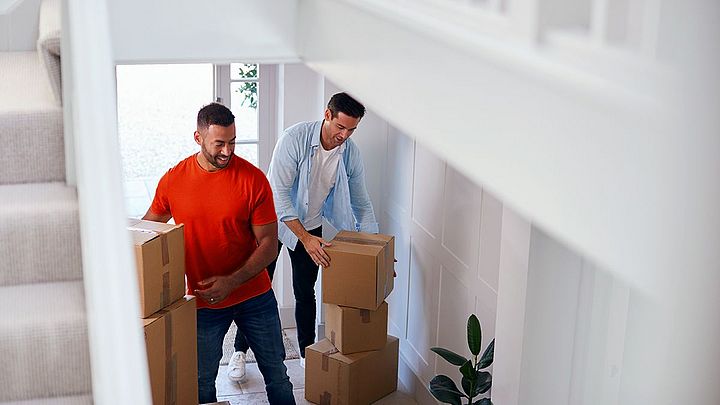 Zwei Männer tragen Umzugskartons in ihr neues Zuhause