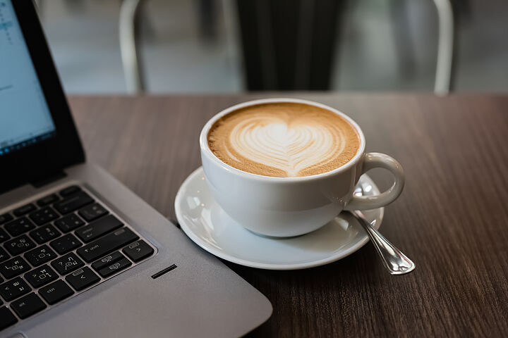 Eine Tasse Kaffee steht neben einem Laptop.