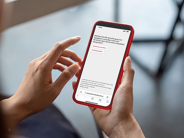 Ein Smartphone wird in der Hand gehalten während der digitale Gesundheitsassistent XUND geöffnet ist.