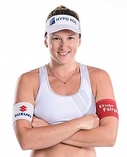 Porträtfoto einer Beachvolleyballspielerin mit verschränkten Armen und einem Lächeln.