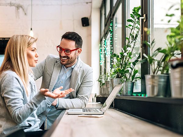 Zwei junge Geschäftsleute haben ein Meeting vor einem Laptop.