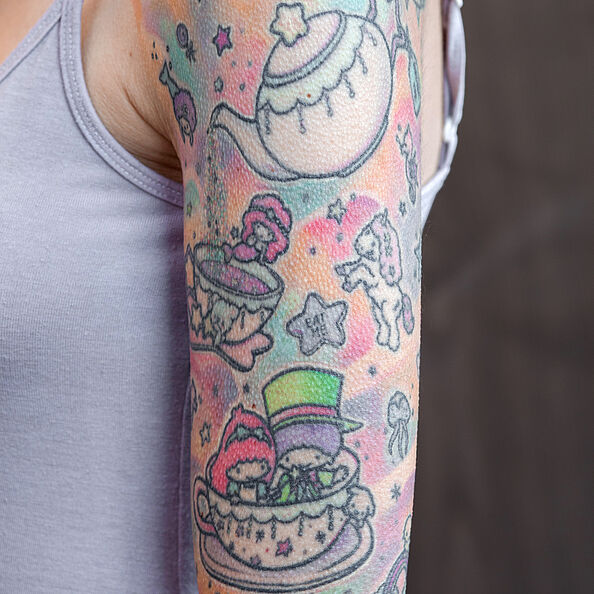 Tätowierter Oberarm einer Frau mit bunten Motiven