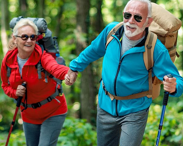 Ein glückliches Seniorenpaar in Sportkleidung wandert durch den Wald