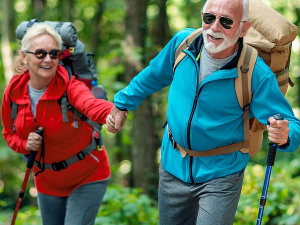 Ein glückliches Seniorenpaar in Sportkleidung wandert durch den Wald