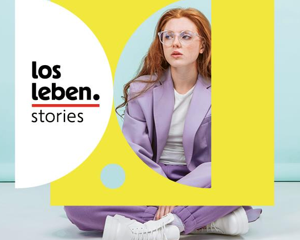 Junge, rothaarige Frau mit weißen Sneackerl und violettem Hosenanzug sitzt am Boden. Daneben erscheint das losleben.stories Logo.