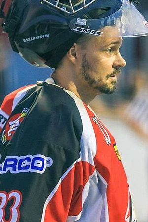 Claudio Mette, ein Außendienstmitarbeiter der Wiener Städtischen, steht am Eishockey Feld mit entsprechender Ausrüstung und nimmt konzentriert am Spiel teil