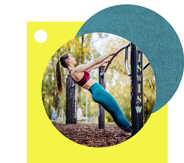 Eine sportliche Frau mit Pferdeschwanz führt in einem Outdoor-Fitnesspark eine Schrägliegestütz-Übung an einer Metallstange aus.