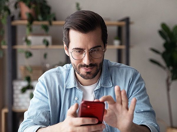 Ein Mann hält ein Smartphone in der Hand und navigiert sich durch die Funktionen