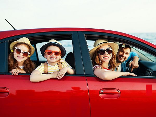 Eine glückliche Familie - Vater, Mutter und Kinder fahren mit dem Auto in den Urlaub.