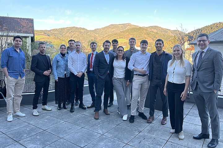 Gruppenfoto beim Ausbildungsstart der Financial Life Coaches auf einer Terrasse mit Berge im Hintergrund.