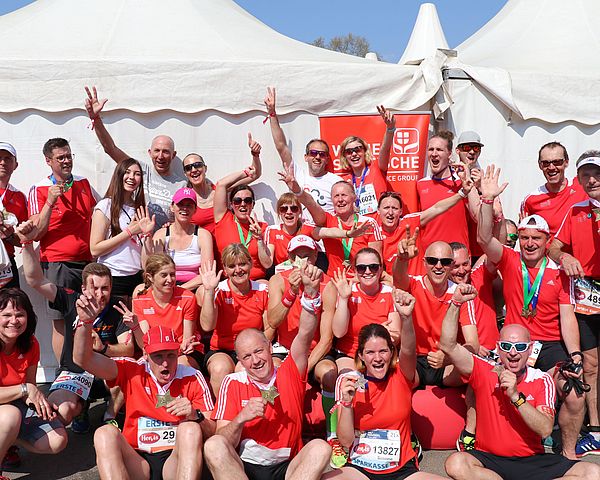 Marathonläufer stehen für ein Gruppenfoto beisammen und jubeln.