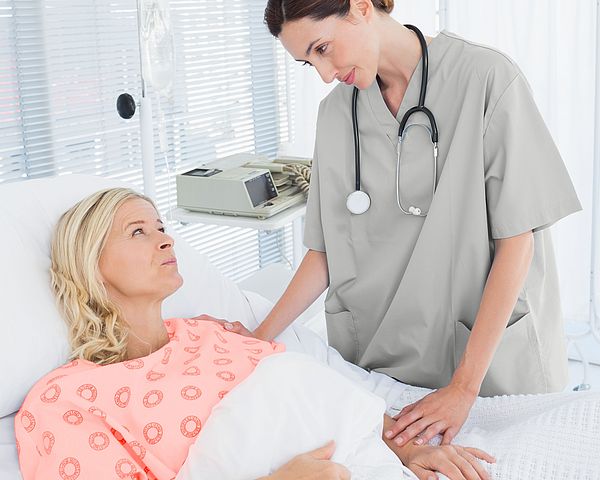 Eine Ärztin kümmert sich um eine Patientin im Krankenhaus, welche im Krankenbett liegt.