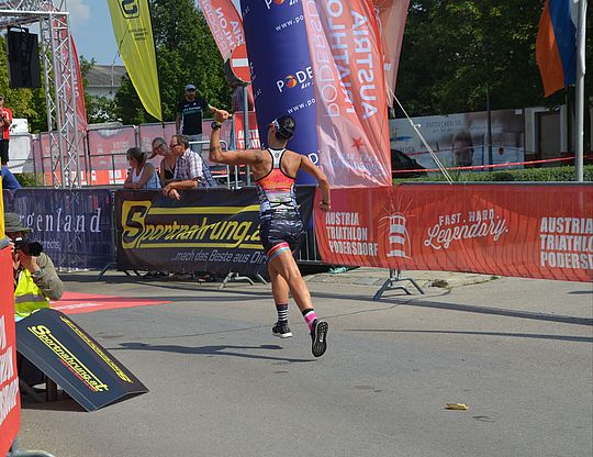 Ein Marathonläufer in Sportklamotten läuft mit Händen in der Höhe durchs Ziel