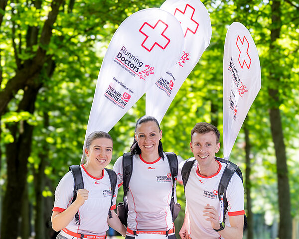 Teilnehmer und Teilnehmerinnen die als Running Doctor mit einer Beach Flag am Rücken bei einem Marathon mitlaufen.