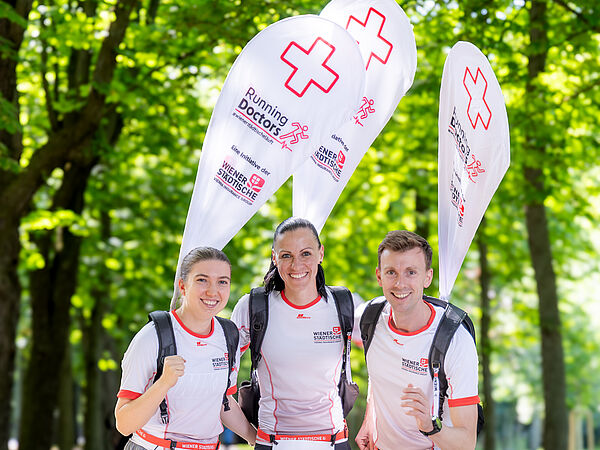 Teilnehmer und Teilnehmerinnen die als Running Doctor mit einer Beach Flag am Rücken bei einem Marathon mitlaufen.