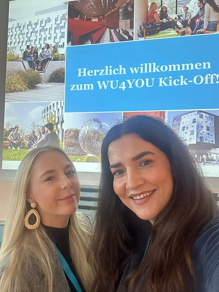 Selfi bei der WU4YOU-Kick-Off-Veranstaltung. Im Hintegrund ist die erste Folie der Präsentation zu sehen.