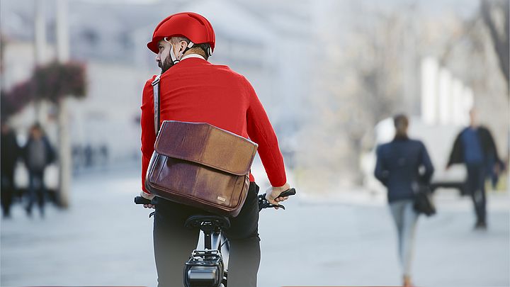 Ein Mann mit Helm fährt mit seinem Fahrrad durch die Stadt.