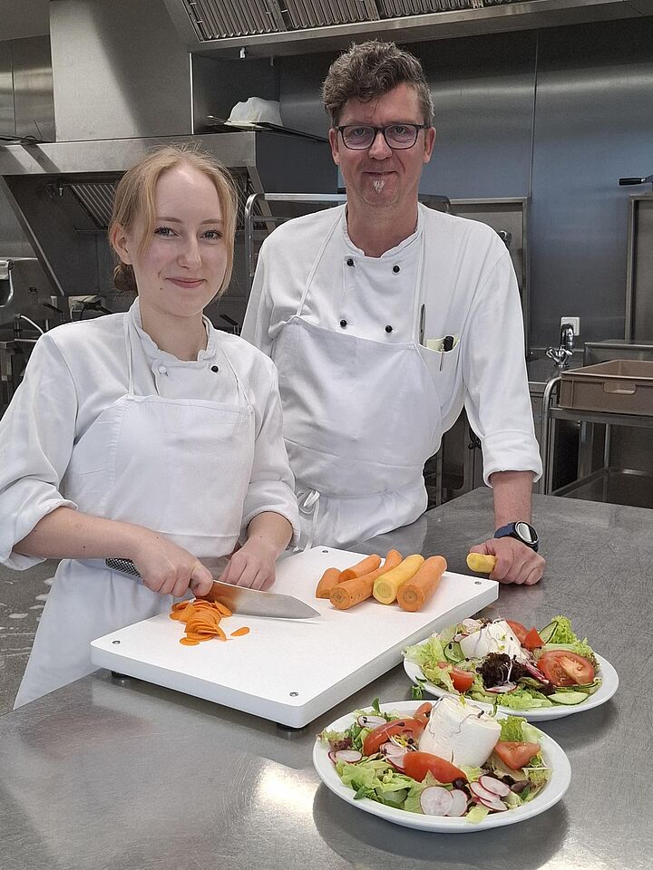 Zwei Personen (ein Koch und eine Köchin) in der Betriebsküche.