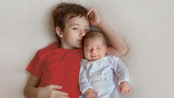 Junge und Baby liegen nebeneinander.