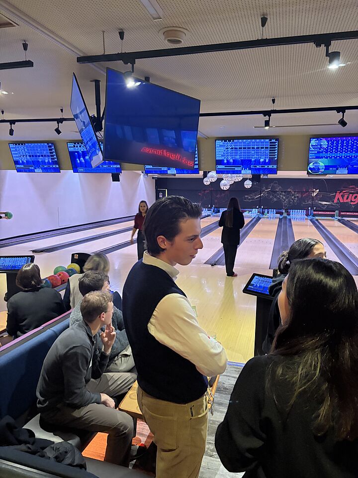 Auf dem Bild sieht man eine Bowlingbahn und sich unterhaltende Leute