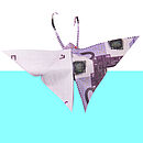 Ein aus einem Geldschein gefalteter Schmeterling mit dreieckigen Flügeln auf weißem und hellblauem Hintergrund