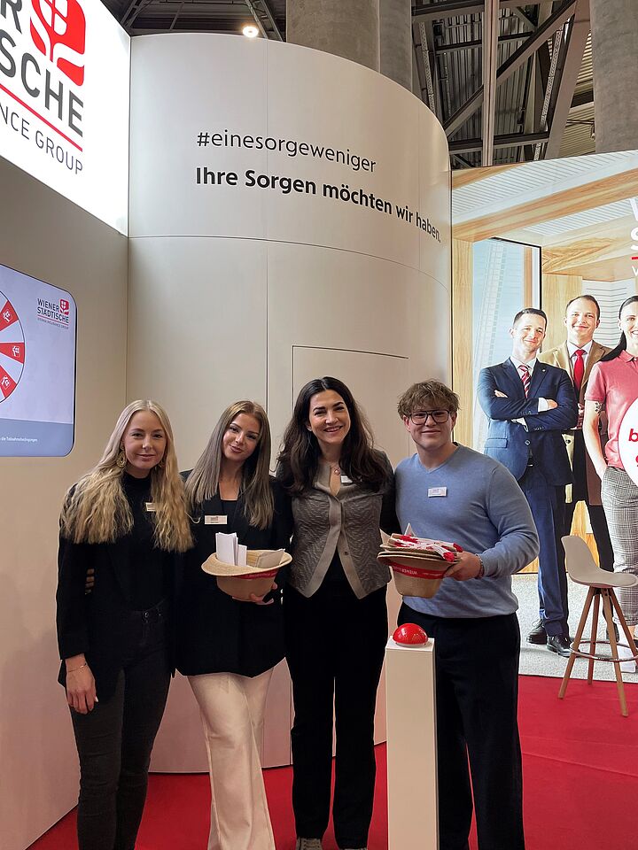 Gruppenfoto von vier Personen auf einer Jobmesse beim Messestand mit digitalem Glücksrad.