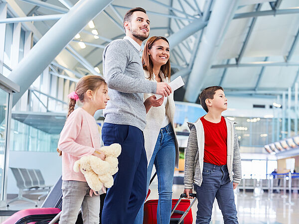 Eine junge Familie wartet voller Freude am Flughafen auf ihren Abflug in den Urlaub.