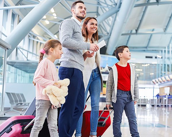 Eine junge Familie wartet voller Freude am Flughafen auf ihren Abflug in den Urlaub.