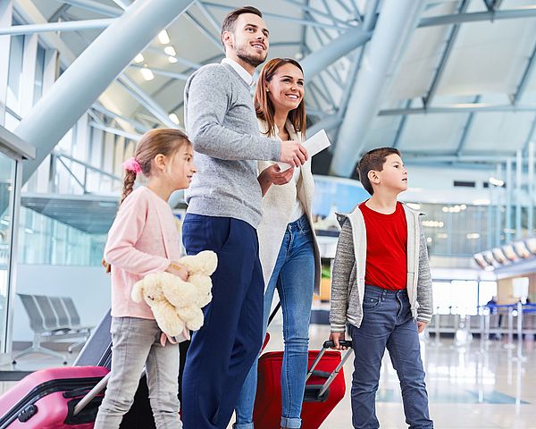 Eine junge Familie wartet voller Freude am Flughafen auf ihren Abflug in den Urlaub.