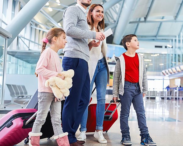 Eine junge Familie wartet voller Freude am Flughafen auf ihren Abflug in den Urlaub.